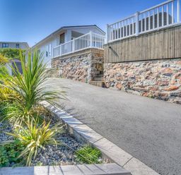 A driveway beside a stone wall with plants along the edge at The Warren Q4 in Abersoch