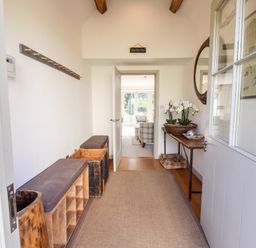 A hallway with benches shoe storage and a table with flowers at Stow Cottage Barn in Churchill Oxfordshire