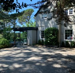 An exterior view of a two story house with multiple windows and surrounding trees at Landmark in Salcombe