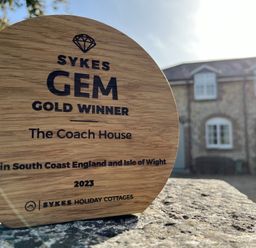 A wooden award on a stone surface with a house in the background at The Coach House at Lackington Farm in Piddletrenthide