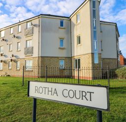A lawn in front of a multi-story residential building with balconies and satellite dishes at Rotha Court