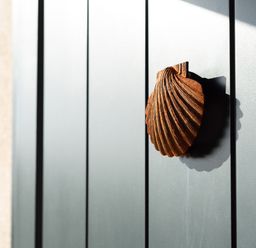 A close up of a brown shell shaped door knocker on a gray door at Church Rooms in Port Isaac