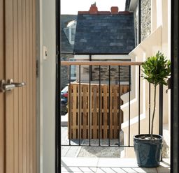 A small balcony with a potted plant and a metal railing outside a door at Church Rooms in Port Isaac