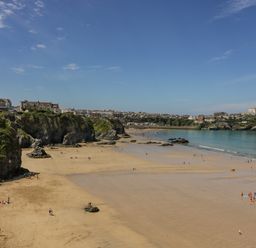 A sandy beach with people near cliffs and houses overlooking the sea at 13 Cliff Edge in Newquay