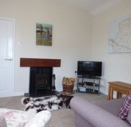 A living room with a fireplace a television on a stand and a sofa at Hafod Cottage in Cemaes Bay