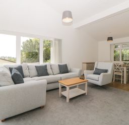 A living room with sofa armchair coffee table and dining area with table and chairs at Harcombe House Bungalow 3 in Chudleigh