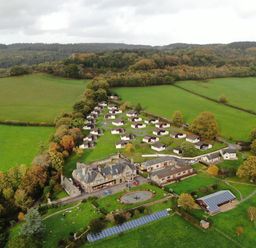 Aerial view of a rural property with multiple bungalows a large house solar panels tennis courts and surrounding fields at Harcombe House  Bungalow 4 in Chudleigh