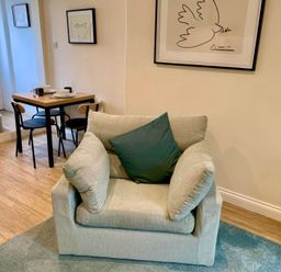 A living room with an armchair and a dining table at Bobbin Cottage in Swanage