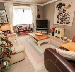 A living room with two sofas a coffee table a television and a window seat at Tartaria in Widdrington