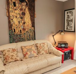 A beige leather sofa with three patterned cushions and a tapestry above it in a living room at Tartaria in Widdrington