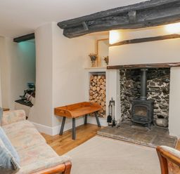 A living room with a fireplace wood stove sofa and a wooden bench at Ashness in Bassenthwaite near Keswick