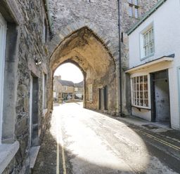 A stone archway over a narrow street with buildings on both sides at 1 Tower House in Cartmel