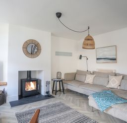 A living room with a fireplace a large sofa and a television at Disgwylfa in Moelfre