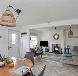 A living and dining area with a round wooden table and chairs a fireplace and a sofa at Disgwylfa in Moelfre