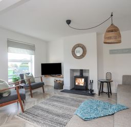 A living room with two armchairs a sofa a fireplace and a television at Disgwylfa in Moelfre