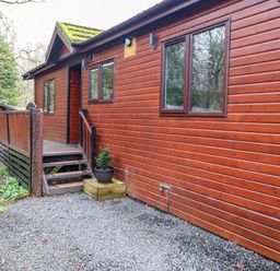 An exterior view of a wooden cabin with a small staircase and gravel pathway at Alfresco Lodge in Skiptory Howe 37B White Cross Bay near Windermere