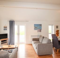 A living room with sofas coffee table tv and dining table at Beside the Sea in Eype