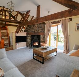 A living room with two sofas wooden beams stone fireplace and a coffee table at Oak Cottage in North Molton