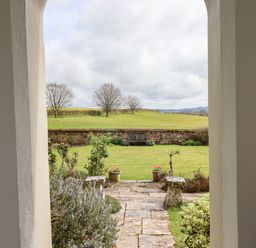 A stone pathway leading to a garden with a bench and green grass at Crablake Farmhouse in Exminster