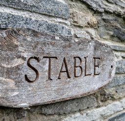 A wooden sign with the word Stable on a stone wall at Stable Cottage in Port Isaac