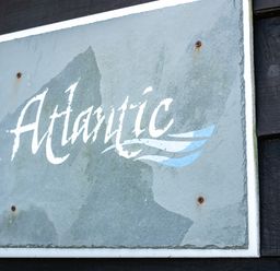 A weathered sign with the word Atlantic mounted on a dark wooden wall at Atlantic Lodge in Port Isaac