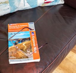 A leather couch with a pair of glasses and a Newquay and Padstow explorer map at Gull Lodge in Port Isaac
