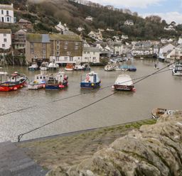 A harbor with moored boats and houses on hills in the background at Spindrift in Polperro