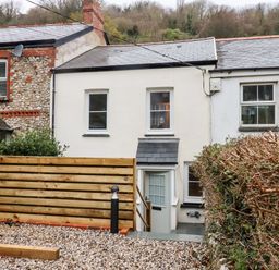 A row of houses with a gravel yard and wooden fence at Beach Road House in Hele Bay Ilfracombe