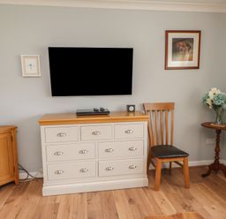 A living room with furniture including a television and wooden chair at Bro Mebyd, Criccieth