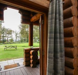 View from inside a wooden log cabin looking out to a grassy area with a picnic table at Brynallt Country Park Frankton near Ellesmere