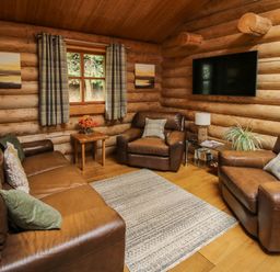 A living room with leather sofas a rug a window and a wall mounted TV at Brynallt Country Park Frankton near Ellesmere