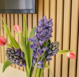 A vase with purple and pink flowers on a white surface in front of a wooden slatted wall at Estuary Walk Whitby