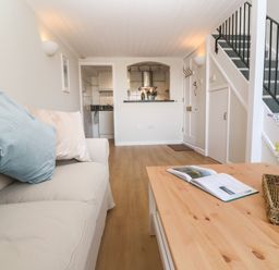 A living room with sofa cushions a wooden coffee table flowers and stairs at 58 High Street in Falmouth