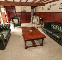 A living room with green leather sofas wooden coffee table and armchairs at The Granary in Longhirst near Morpeth