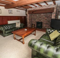 A living room with two green leather sofas a wooden coffee table and a brick fireplace at The Granary in Longhirst near Morpeth