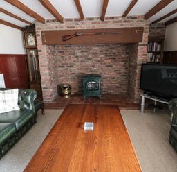 A living room with green leather sofas a wooden coffee table a TV and a brick fireplace at The Granary in Longhirst near Morpeth