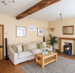 A living room with a beige sofa a wooden coffee table a rug and a fireplace at Above Deck in Beaumaris