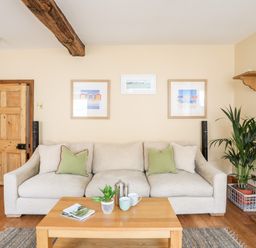 A living room with a beige sofa green cushions wooden coffee table and framed pictures on the wall at Above Deck in Beaumaris