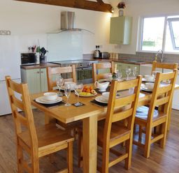 A kitchen with a wooden dining table set with dishes and glasses at Haimwood Byetake in Llandrinio