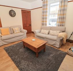 A living room with two sofas a wooden coffee table a floor lamp and a gray rug at Coras House in Amble