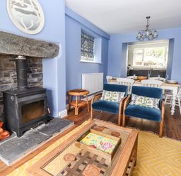 A living room with a wood burner fireplace blue armchairs and dining table at Estcote Roger Ground near Hawkshead