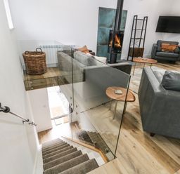 A living room with a wood stove tv armchairs and sofas viewed from a stairway at Bank Hurst Coach House in Ulverston