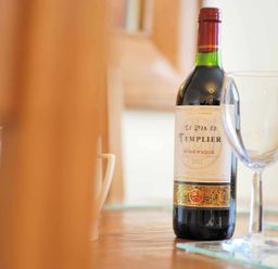 A bottle of red wine and an empty wine glass on a table at House on the Green in Chipping Norton