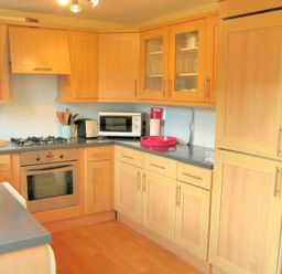 A kitchen with wooden cabinets a gas stove an oven a microwave and a refrigerator at House on the Green in Chipping Norton