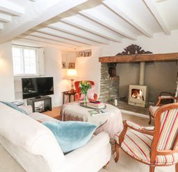 A sitting room with a sofa chairs a coffee table and a fireplace at Holly Cottage in Minster Lovell
