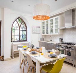 A kitchen with a white table set for breakfast and stainless steel appliances at Little Culver in Minchinhampton