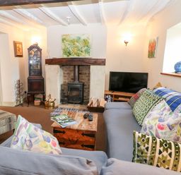 A living room with a fireplace television and a sofa with cushions at Carters Cottage in Stow on the Wold