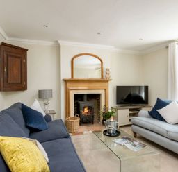A living room with two sofas a glass coffee table a fireplace and a television at Copperbeech in Stow-on-the-Wold