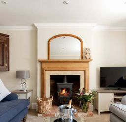 A living room with a fireplace a mirror a television and sofas at Copperbeech in Stow-on-the-Wold