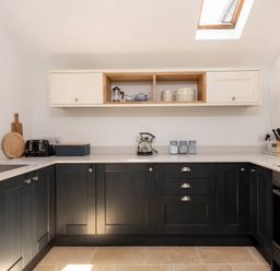 A kitchen with black lower cabinets white upper cabinets toaster kettle and knife block at Copperbeech in Stow on the Wold